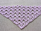 Close-up shot of intricate lace stitches and openwork mesh texture on a crochet bandana shawl.
