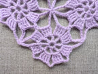 Close-up shot of intricate lace stitches and openwork mesh texture on a crochet bandana shawl.