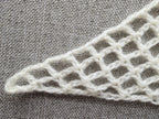 Detailed view of finished edge and lace stitch pattern on a triangle crochet bandana shawl, Chart 5.