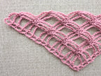 Close-up shot of intricate lace stitches and openwork mesh texture on a crochet bandana shawl.