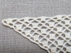 Close-up shot of intricate lace stitches and openwork mesh texture on a crochet bandana shawl.