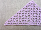 Close-up shot of intricate lace stitches and openwork mesh texture on a crochet bandana shawl.