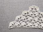 Close-up shot of intricate lace stitches and openwork mesh texture on a crochet bandana shawl.