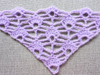 Close-up shot of intricate lace stitches and openwork mesh texture on a crochet bandana shawl.