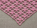 Close-up shot of intricate lace stitches and openwork mesh texture on a crochet bandana shawl.
