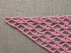 Close-up shot of intricate lace stitches and openwork mesh texture on a crochet bandana shawl.