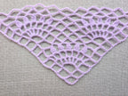 Close-up shot of intricate lace stitches and openwork mesh texture on a crochet bandana shawl.