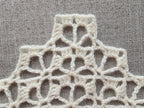 Close-up shot of intricate lace stitches and openwork mesh texture on a crochet bandana shawl.