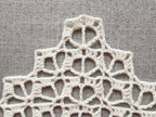 Close-up shot of intricate lace stitches and openwork mesh texture on a crochet bandana shawl.