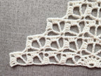 Close-up shot of intricate lace stitches and openwork mesh texture on a crochet bandana shawl.