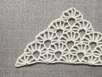 Close-up shot of intricate lace stitches and openwork mesh texture on a crochet bandana shawl.