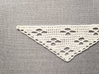 Close-up shot of intricate lace stitches and openwork mesh texture on a crochet bandana shawl.