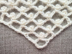 Close-up shot of intricate lace stitches and openwork mesh texture on a crochet bandana shawl.