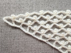 Detailed view of finished edge and lace stitch pattern on a triangle crochet bandana shawl, Chart 23.