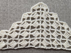 Close-up shot of intricate lace stitches and openwork mesh texture on a crochet bandana shawl.