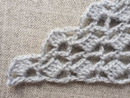 Close-up shot of intricate lace stitches and openwork mesh texture on a crochet bandana shawl.