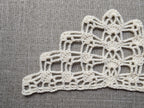 Close-up shot of intricate lace stitches and openwork mesh texture on a crochet bandana shawl.
