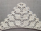 Close-up shot of intricate lace stitches and openwork mesh texture on a crochet bandana shawl.