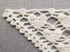 Close-up shot of intricate lace stitches and openwork mesh texture on a crochet bandana shawl.