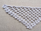 Close-up shot of intricate lace stitches and openwork mesh texture on a crochet bandana shawl.