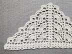 Close-up shot of intricate lace stitches and openwork mesh texture on a crochet bandana shawl.