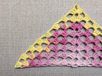 Close-up shot of intricate lace stitches and openwork mesh texture on a crochet bandana shawl.