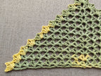 Close-up shot of intricate lace stitches and openwork mesh texture on a crochet bandana shawl.