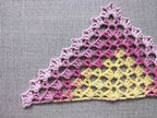 Close-up shot of intricate lace stitches and openwork mesh texture on a crochet bandana shawl.