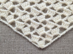 Close-up shot of intricate lace stitches and openwork mesh texture on a crochet bandana shawl.