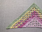 Close-up shot of intricate lace stitches and openwork mesh texture on a crochet bandana shawl.