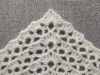 Close-up shot of intricate lace stitches and openwork mesh texture on a crochet bandana shawl.
