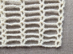 Close-up shot of intricate lace stitches and openwork mesh texture on a crochet scarf.