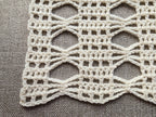 Close-up shot of intricate lace stitches and openwork mesh texture on a crochet scarf.