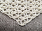 Close-up shot of intricate lace stitches and openwork mesh texture on a triangle baktus crochet shawl.