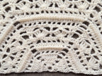 Close-up shot of intricate lace stitches and openwork mesh texture on a trapezoid crochet shawl.