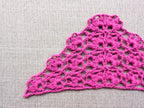 Close-up shot of intricate lace stitches and openwork mesh texture on a crochet bandana shawl.