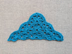 Close-up shot of intricate lace stitches and openwork mesh texture on a triangle crochet shawl.