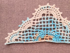 Close-up shot of intricate lace stitches and openwork mesh texture on a crochet bandana shawl.
