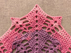 Close-up shot of intricate lace stitches and openwork mesh texture on a triangle crochet shawl.