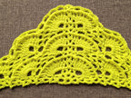 Close-up shot of intricate lace stitches and openwork mesh texture on a triangle crochet shawl.