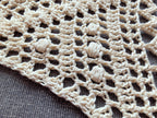 Close-up shot of intricate lace stitches and openwork mesh texture on a triangle crochet shawl.