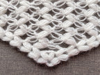 Close-up shot of intricate lace stitches and openwork mesh texture on a triangle baktus crochet shawl.