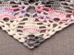 Close-up shot of intricate lace stitches and openwork mesh texture on a triangle crochet shawl.