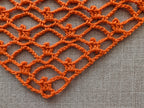 Close-up shot of intricate lace stitches and openwork mesh texture on a crochet bandana shawl.