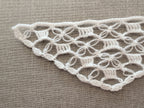 Close-up shot of intricate lace stitches and openwork mesh texture on a crochet bandana shawl.