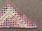 Close-up shot of intricate lace stitches and openwork mesh texture on a crochet bandana shawl.
