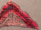 Close-up shot of intricate lace stitches and openwork mesh texture on a crochet bandana shawl.