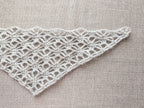 Close-up shot of intricate lace stitches and openwork mesh texture on a triangle crochet shawl.