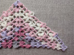 Close-up shot of intricate lace stitches and openwork mesh texture on a triangle crochet shawl.