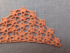 Close-up shot of intricate lace stitches and openwork mesh texture on a triangle crochet shawl.